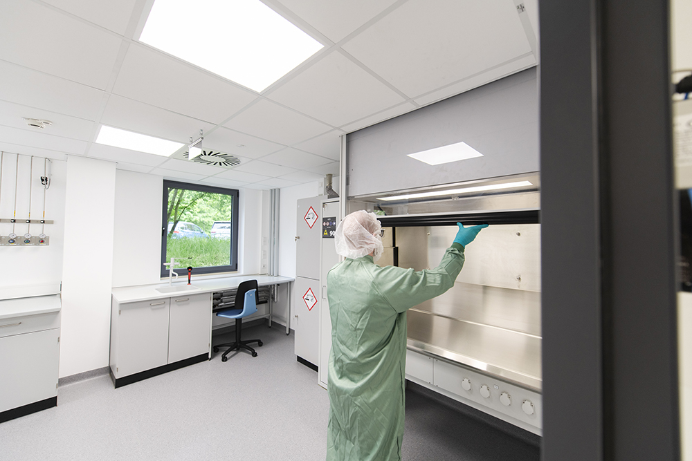 A technician in protective gear works in a process development lab, showcasing CDMO services in a clean, modern facility.