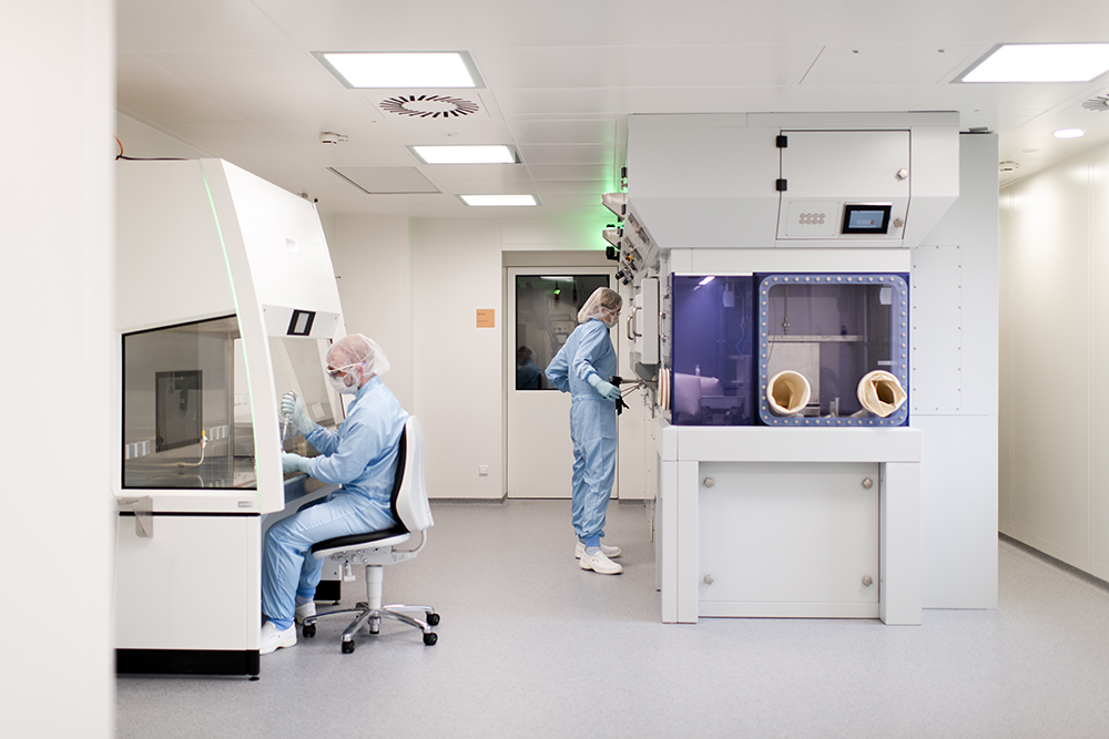 Technicians in protective suits work in a clean room lab with laminar flow and advanced hot cells, showcasing CDMO services for radiopharmaceuticals