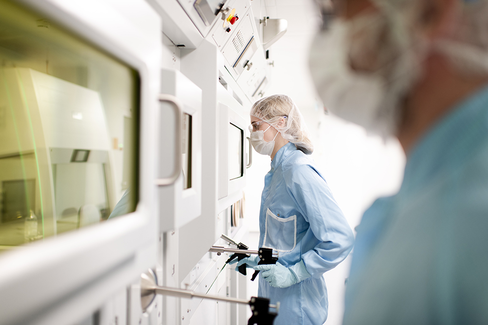 A technician in protective gear operates a hot cell at the ROTOP clean room facility, showcasing CDMO services expertise.