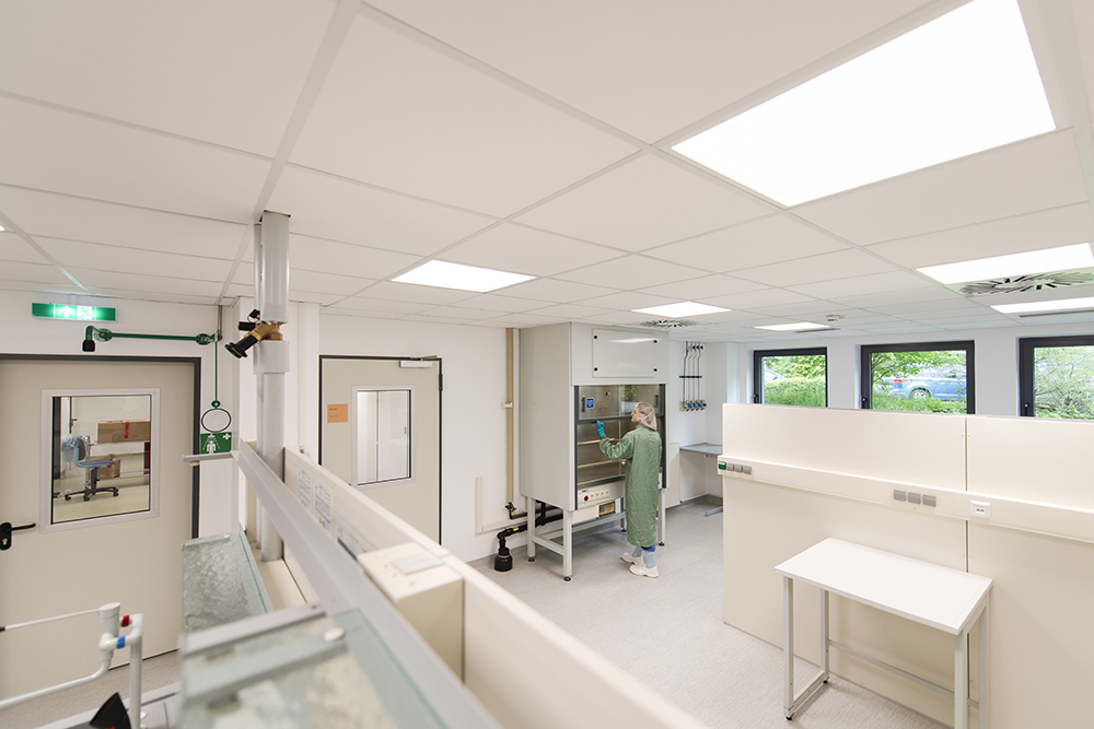 A scientist in a spacious clean lab works with equipment, showcasing CDMO services designed for flexibility and adaptability.