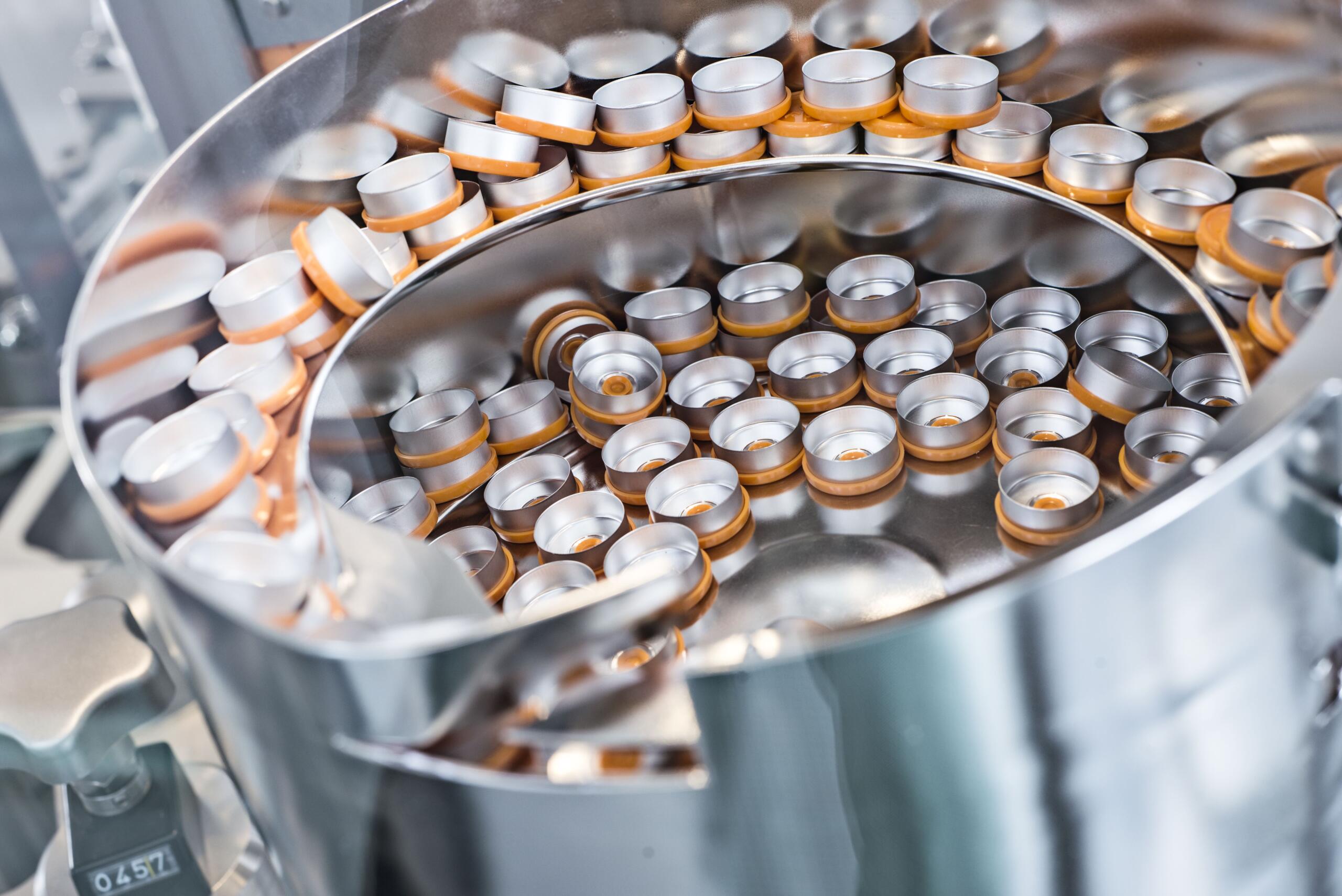 Close-up of the stopper bowl in ROTOP’s cleanroom during GMP production of cold kits, filled with orange vial caps.