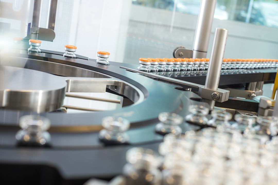 Automated ROTOP cleanroom system with crimped vials moving along the conveyor during GMP-compliant Cold Kit production