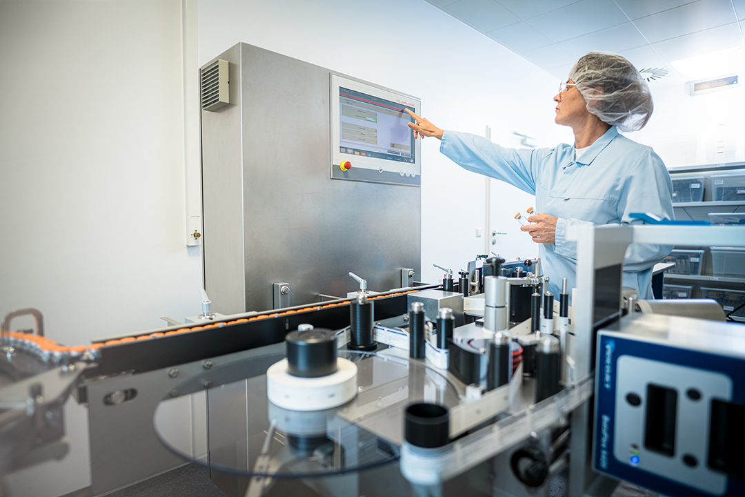 Cleanroom operator handling the labeling machine during GMP production of Cold Kits at ROTOP