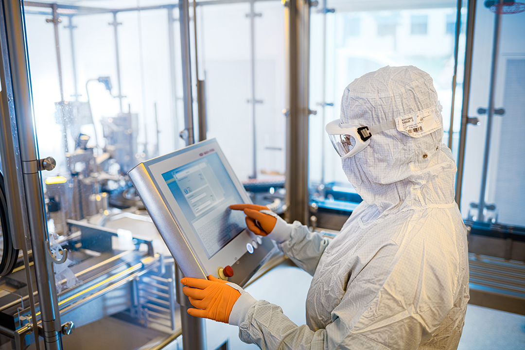 Cleanroom technician operating an automated system via touchscreen for GMP-compliant Cold Kit production at ROTOP