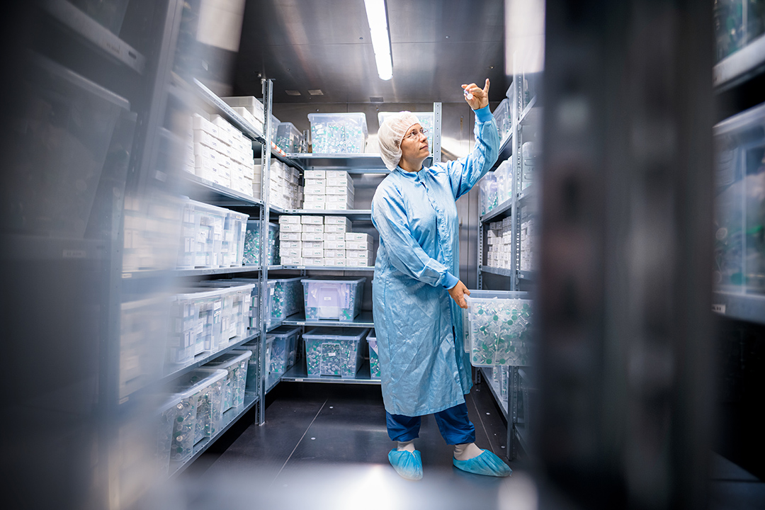 Cleanroom operator standing in ROTOP’s storage area for released medicinal products, holding a vial symbolically