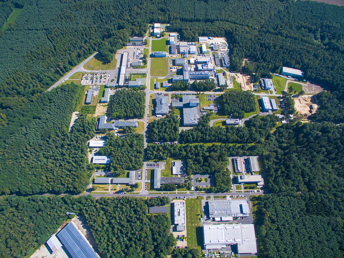 Drone view of the ROTOP building on the green campus of Helmholtz-Zentrum Dresden-Rossendorf (HZDR) surrounded by trees and research facilities